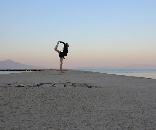 Silhouette of a person balancing in a yoga tree pose during sunset.