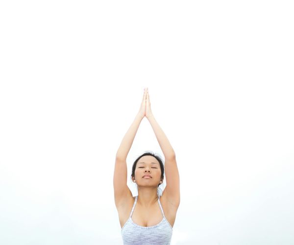 Woman in a peaceful stretching yoga pose against a minimal background.
